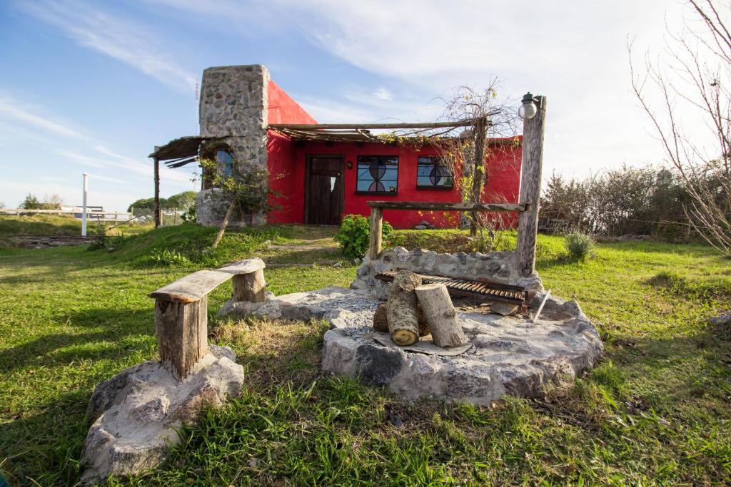 un banco de piedra frente a una casa roja en La Casita Roja, en Colonia del Sacramento