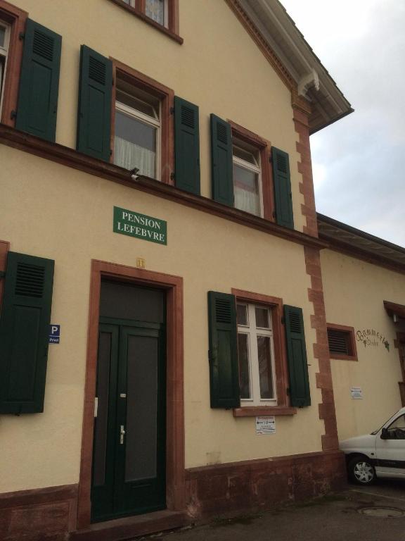 a building with green shuttered windows and a door at Pension Lefebvre in Weil am Rhein