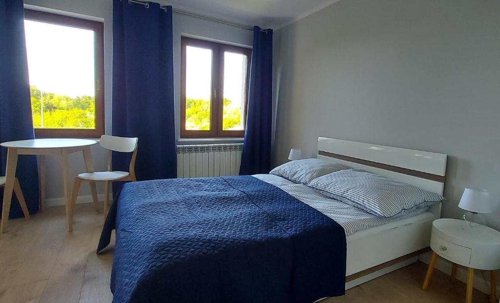1 dormitorio con 1 cama azul y 2 ventanas en Pokoje Gościnne Cztery Wiatry, en Frombork