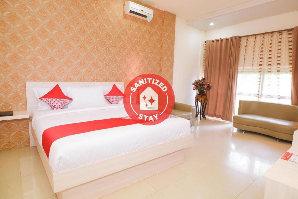 ein Schlafzimmer mit einem Bett und einem Stuhl in einem Zimmer in der Unterkunft Capital O 854 Ub Caisar Hotel in Banda Aceh
