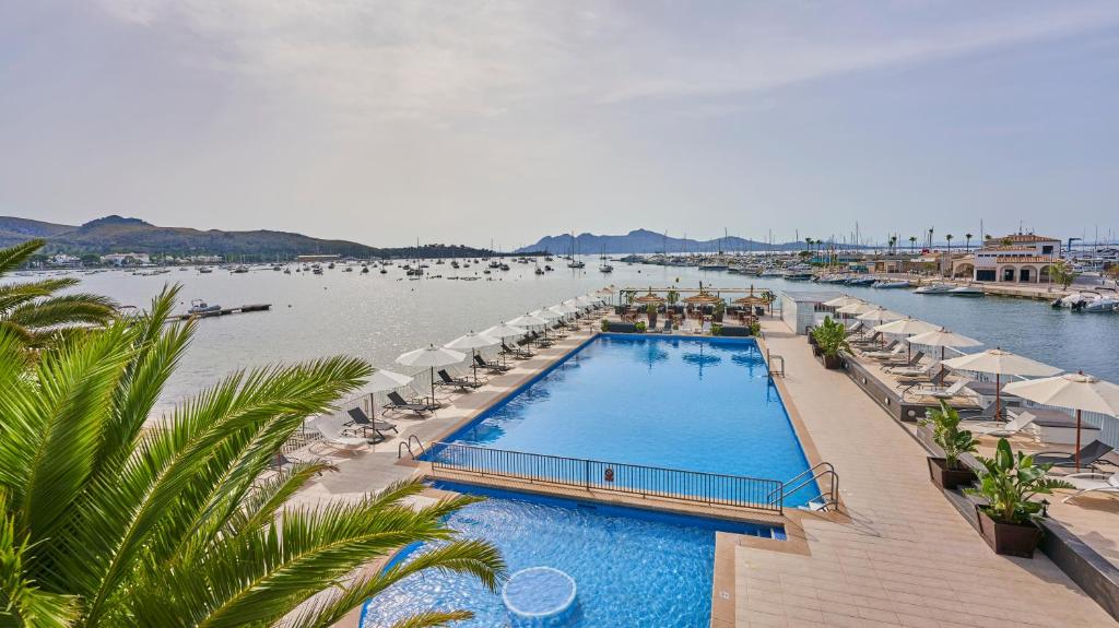 a swimming pool with umbrellas and a body of water at Hoposa Daina- Adults Only in Port de Pollensa