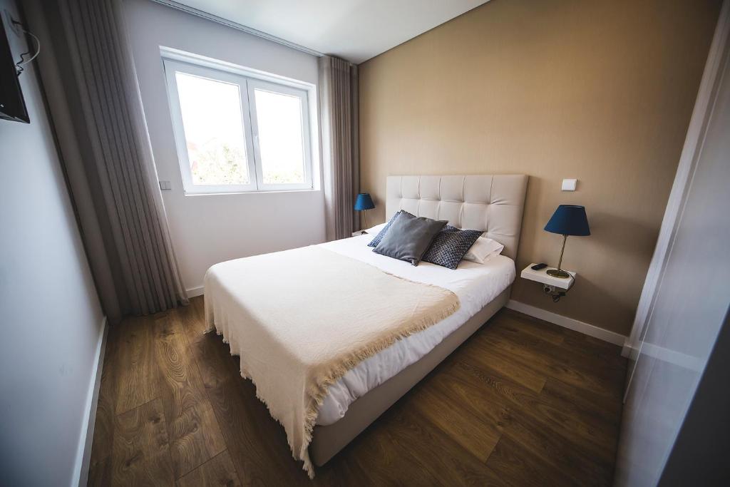 a bedroom with a large white bed with a window at Terro Collection - Anjo in Braga