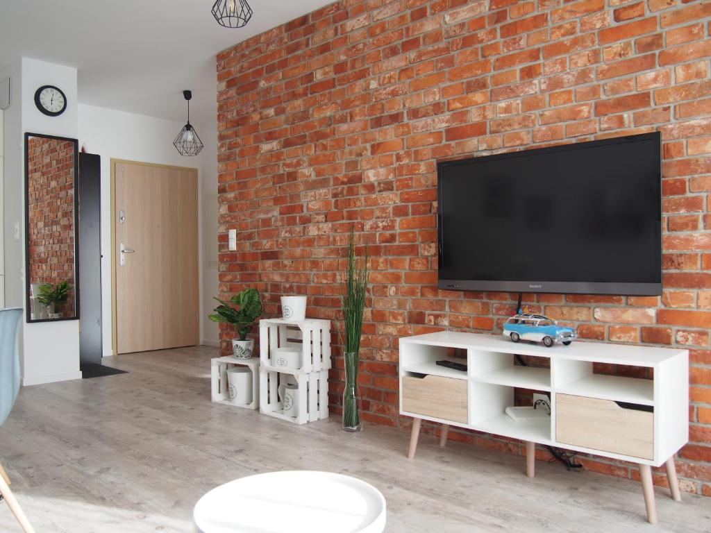 a living room with a brick wall and a tv at Nadmorska Ostoja z prywatnym miejscem postojowym in Pogórze