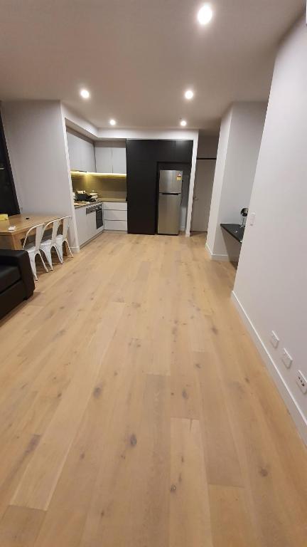 an empty room with a wooden floor and a table at Gardenia Apartment an ideal place to relax and enjoy in Clayton North