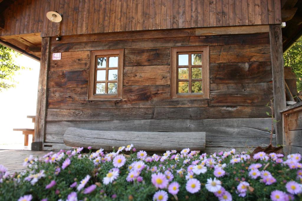 a wooden building with two windows and flowers at Oldhouse Knezovo in Sromlje