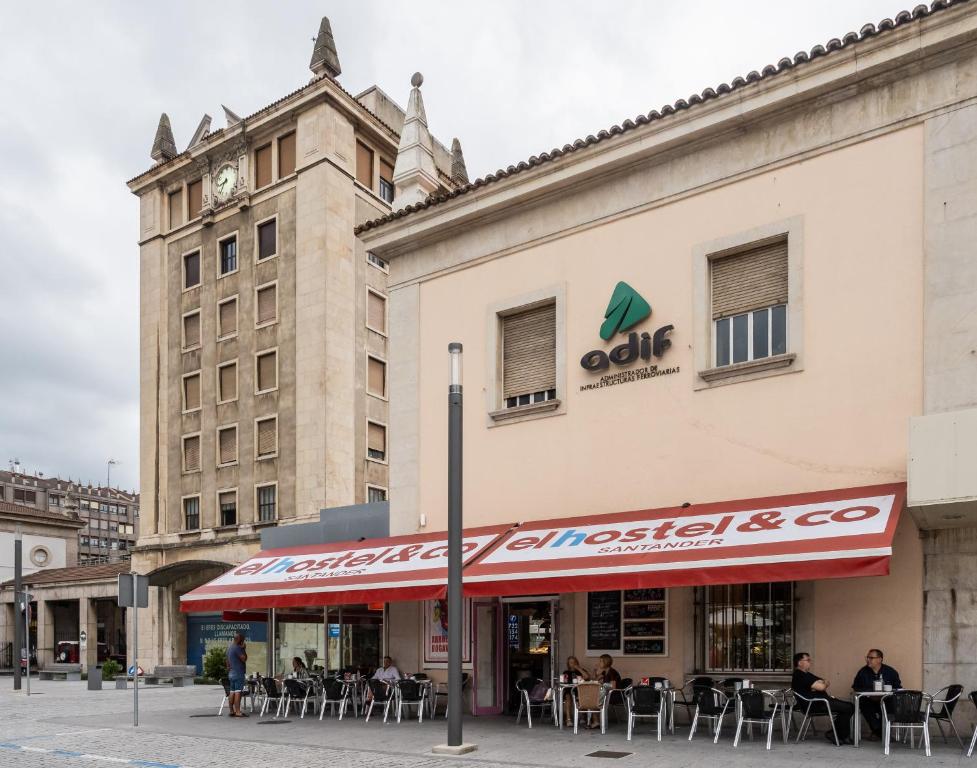 un restaurante con toldo rojo frente a un edificio en El Hostel & CO, en Santander
