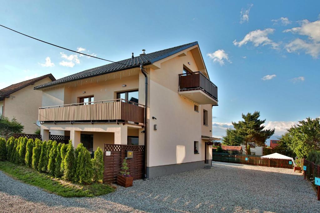 ein weißes Haus mit einem Balkon und einem Zaun in der Unterkunft Apartmany za Rohom in Liptovský Mikuláš