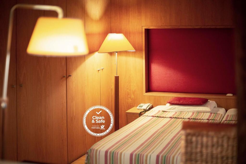 a bedroom with a bed with a lamp and a phone at Apartamentos Turisticos Atlantida in Funchal