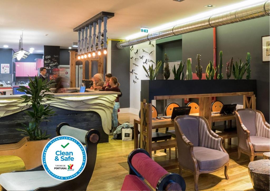 un restaurant avec des chaises et un bar avec un panneau indiquant propreté et sécurité dans l'établissement Nice Way Porto Hostel, à Porto