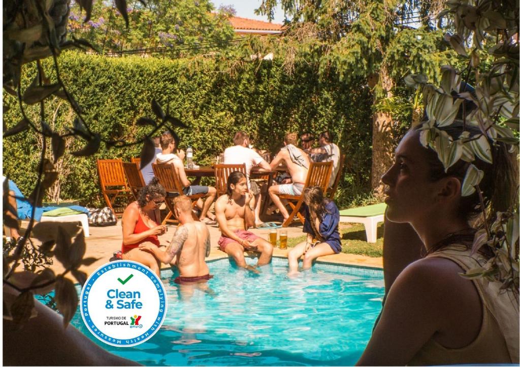 un grupo de personas sentadas en una piscina en Nice Way Cascais Hostel & Surf Camp, en Cascais