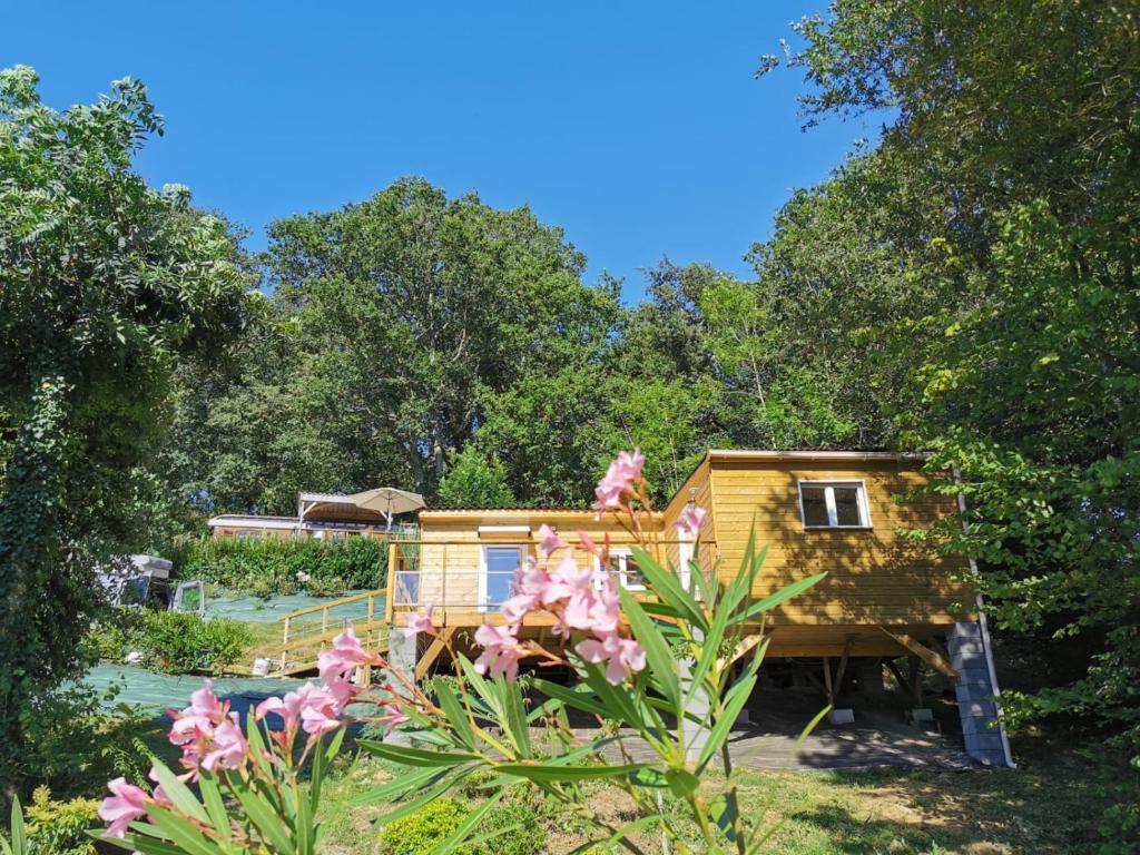 a tiny house in the woods with pink flowers at Le lodge sur pilotis in Fichous-Riumayou