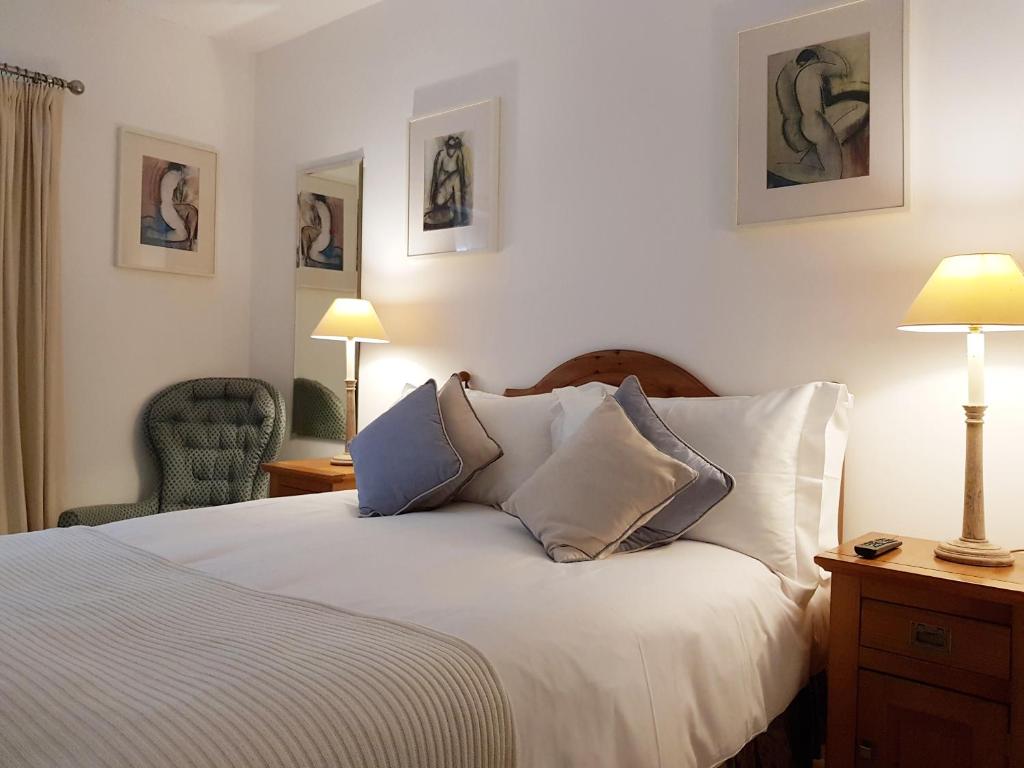 特魯羅的住宿－Chy Bre，一间卧室配有一张带两盏灯和一把椅子的床。