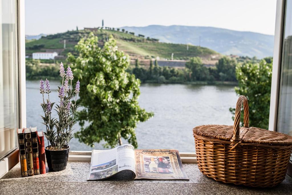 a book and a basket on a window sill with a view at Casa do Rio in Peso da Régua