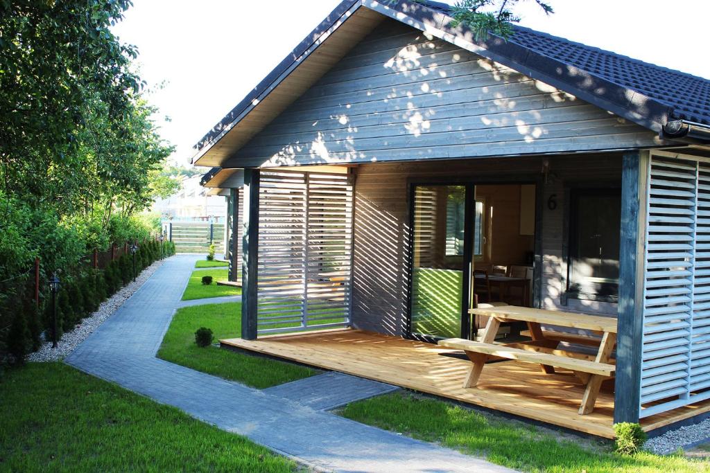 a small cabin with a wooden deck and a bench at luludomki in Mielenko