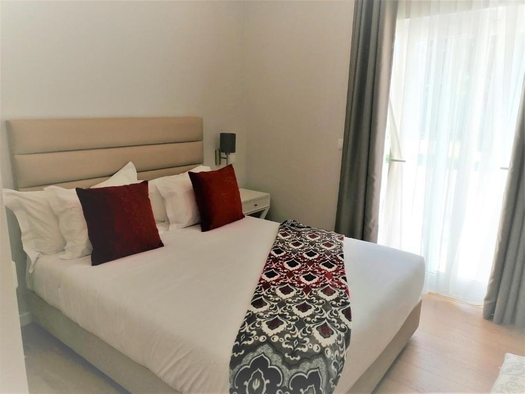 um quarto com uma grande cama branca com almofadas vermelhas em Silver Seahorse Garden Retreat II na Consolação