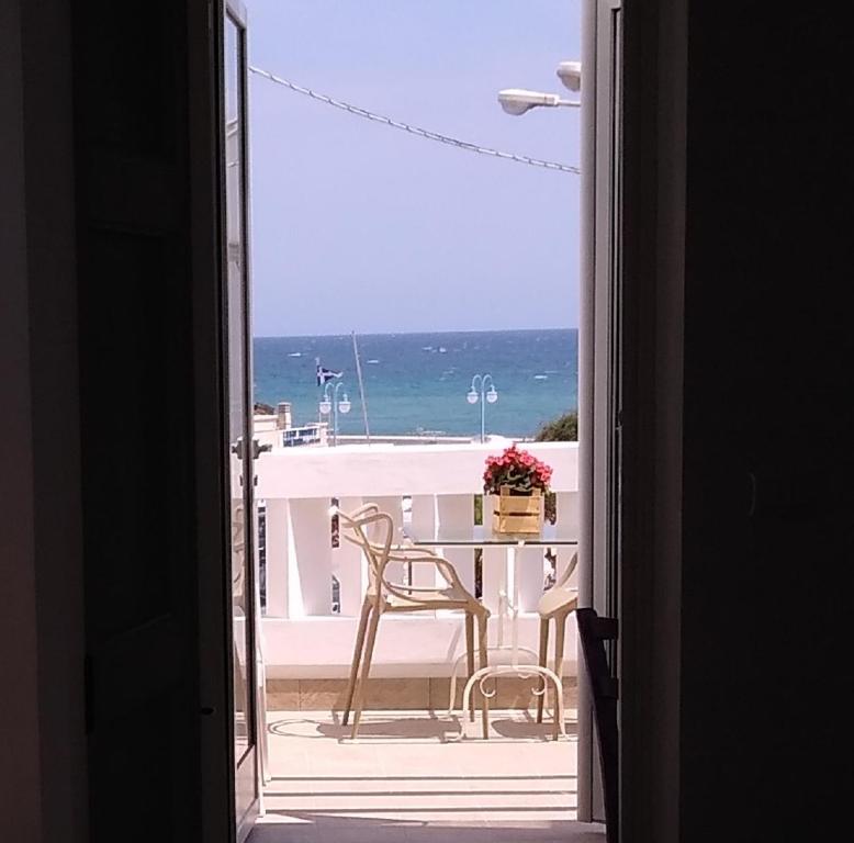 een open deur naar een balkon met een tafel en stoelen bij Casetta Mare in Villanova di Ostuni