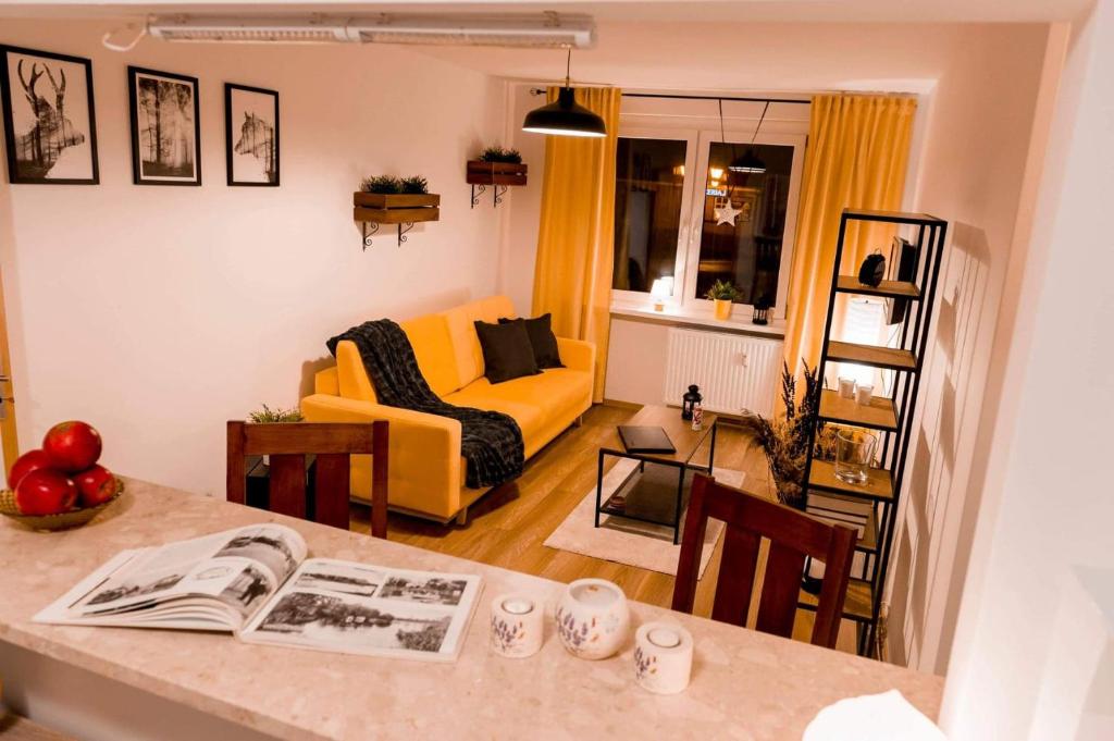 sala de estar con sofá amarillo y mesa en Apartament Słoneczny, en Zbąszyń