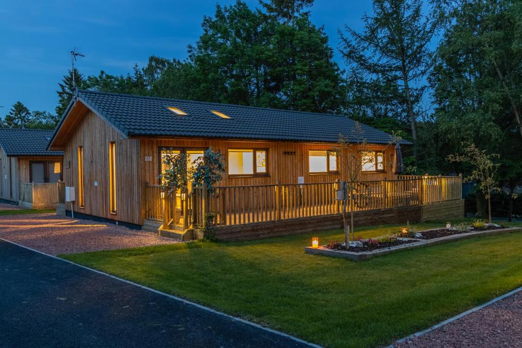 a small house with a fence in a yard at Settlers Lodge in Otterburn