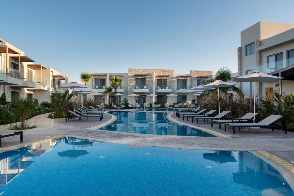 a swimming pool in a resort with chairs and umbrellas at ONEIRO Boutique Hotel in Tigaki