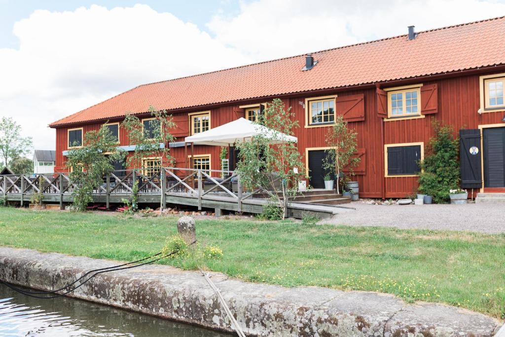 a red building next to a body of water at Kanalmagasinets Pensionat in Söderköping