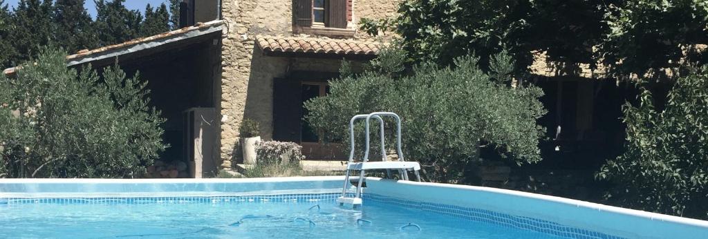 a swimming pool in front of a house at Mas dans la campagne pour loisirs et télétravail in Sarrians