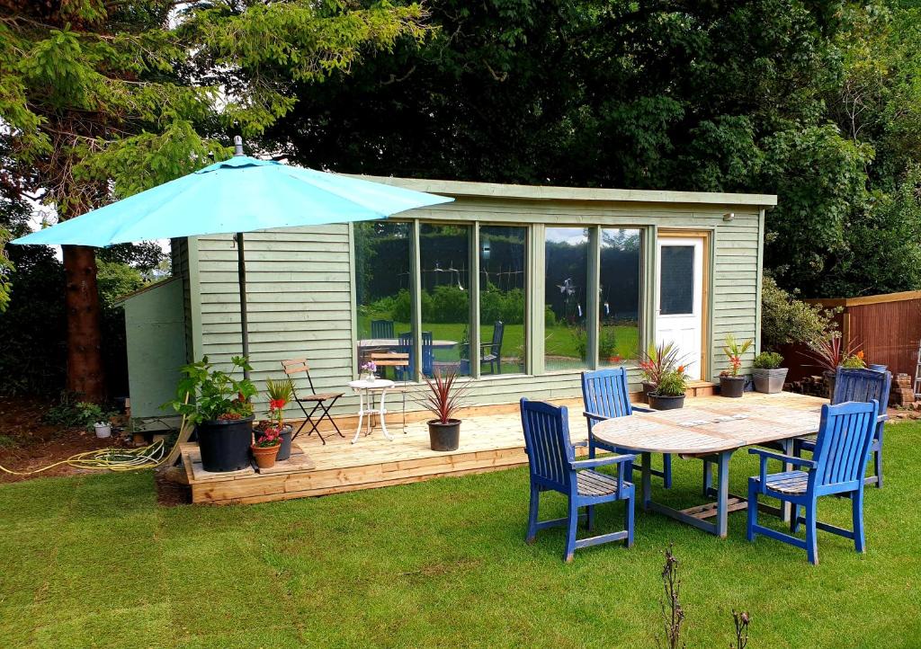 una mesa, sillas y una sombrilla en un patio en The cozy shed, en Stow on the Wold