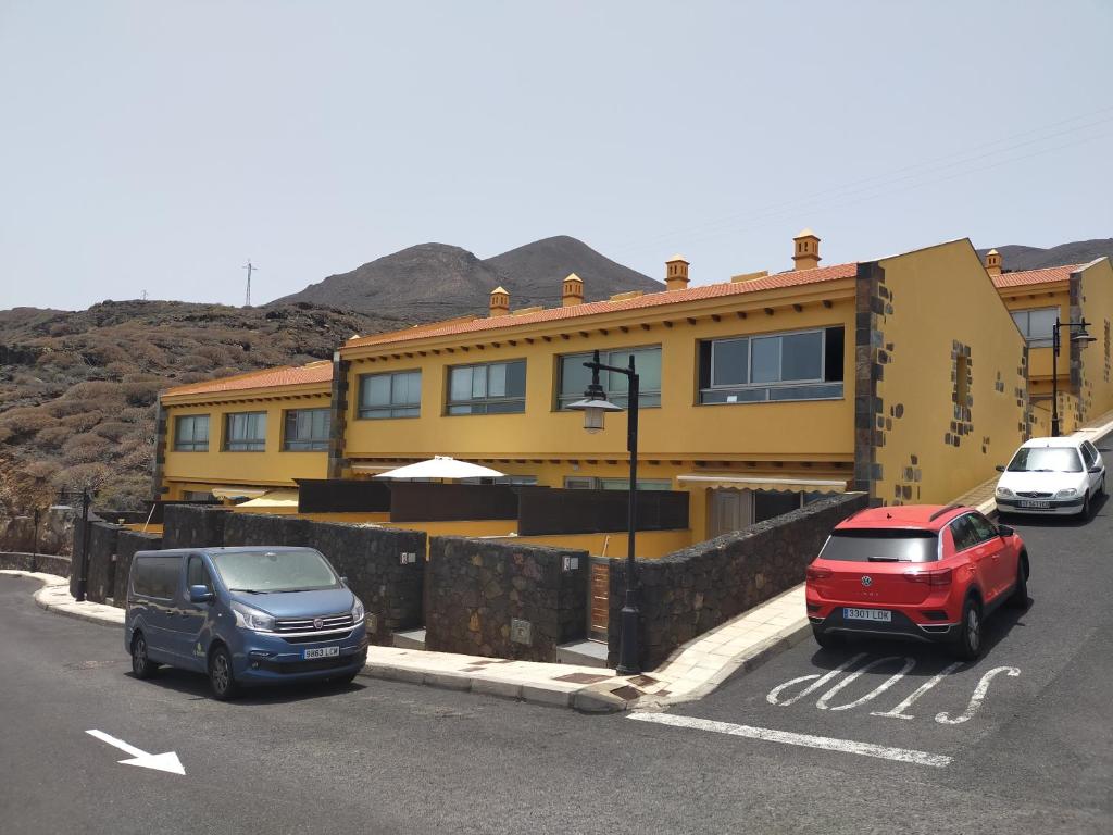 dos autos estacionados frente a una casa amarilla en NAUTILUS II, en La Caleta