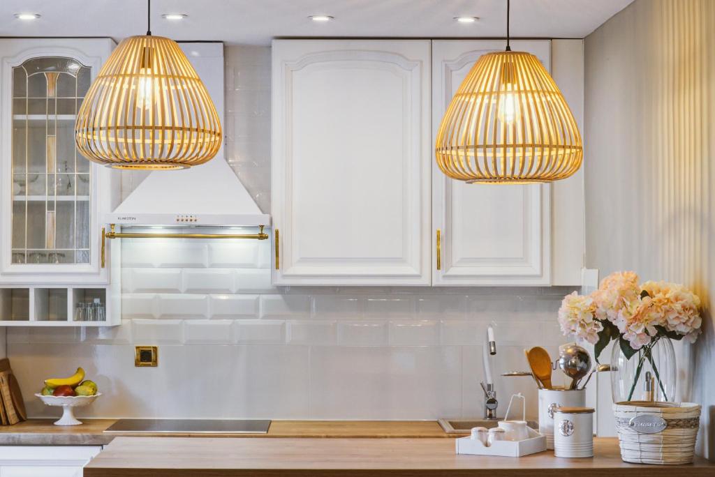 a kitchen with white cabinets and two hanging lights at Apartment Lara in Senj