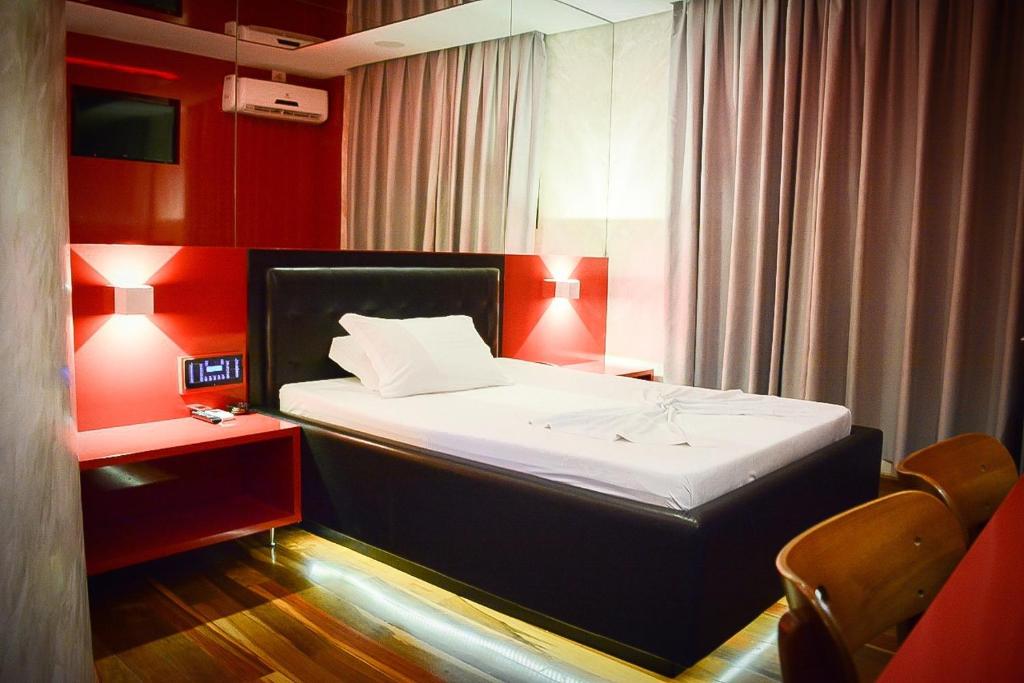 a small bedroom with a bed with red walls at Motel Sunny Day Contagem in Contagem