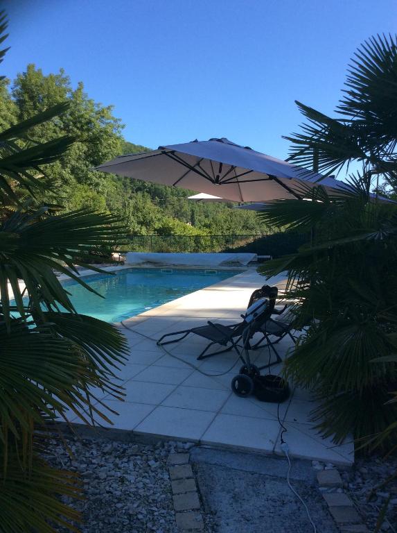 a chair sitting under an umbrella next to a pool at Le Relais du Pech in Carlux