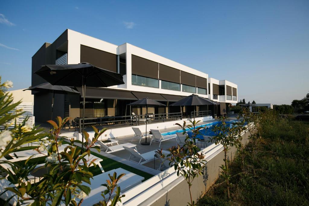 un edificio con una piscina con sombrillas en ISALOS GERAKiNi en Yerakiní