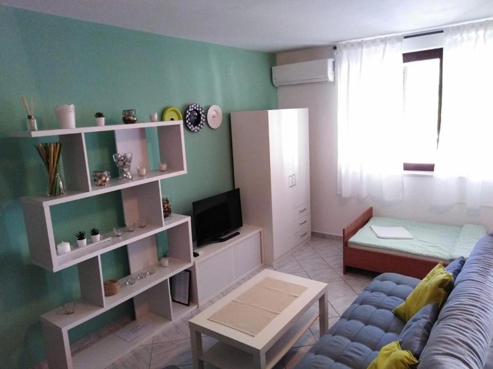 ein Wohnzimmer mit einem blauen Sofa und einem TV in der Unterkunft Apartments L&M in Rogoznica
