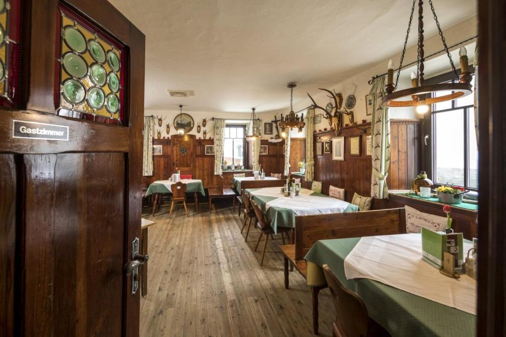 una sala da pranzo con tavoli, sedie e una porta di Gasthof Grüner Baum a Kirchberg am Wechsel