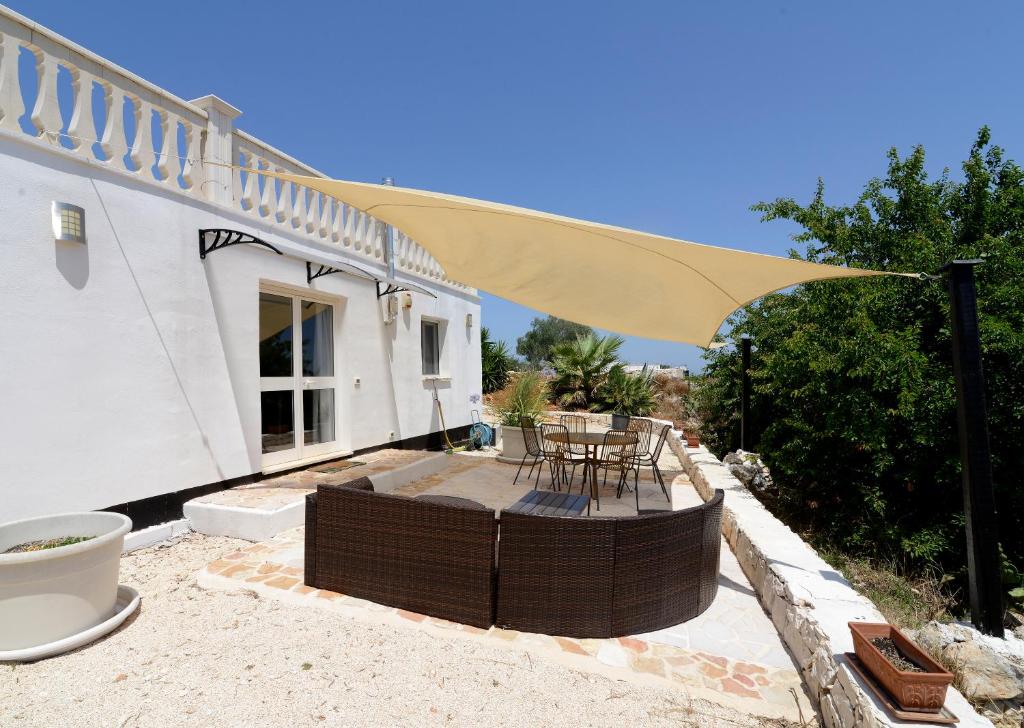 a patio with a table and chairs under a yellow umbrella at Villetta Panoramica in Ostuni