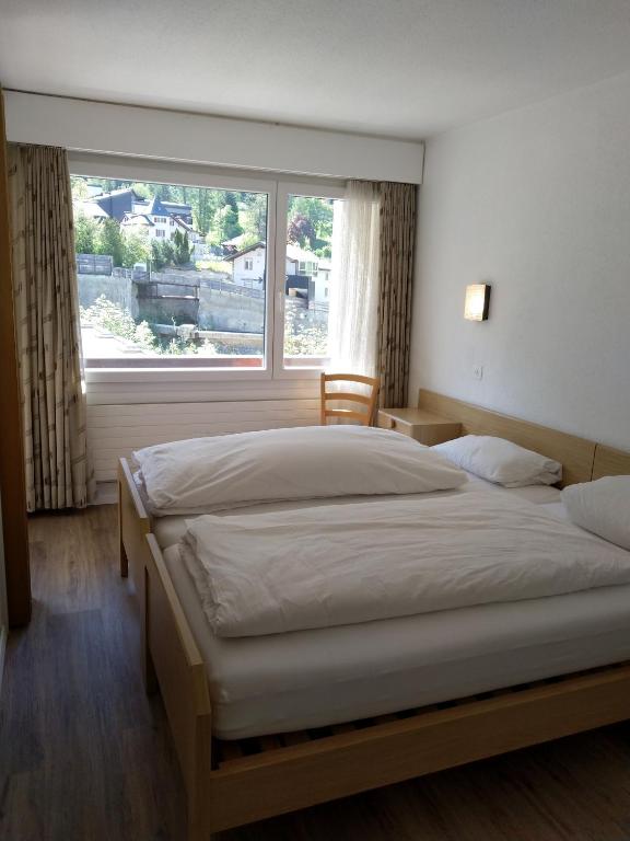 a bedroom with two beds and a large window at Fortuna 404 in Leukerbad