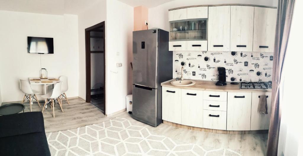 a kitchen with white cabinets and a stainless steel refrigerator at Apartament One Divine - Zarnesti in Zărneşti