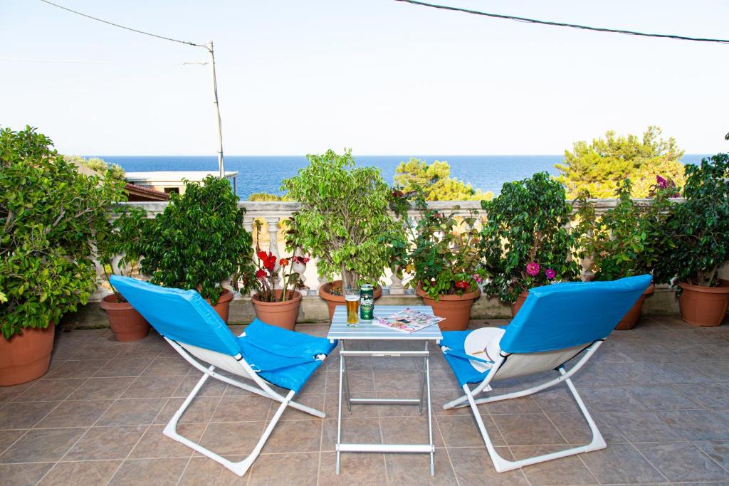 2 blaue Stühle und ein Tisch auf einer Terrasse in der Unterkunft G and A House in Póros