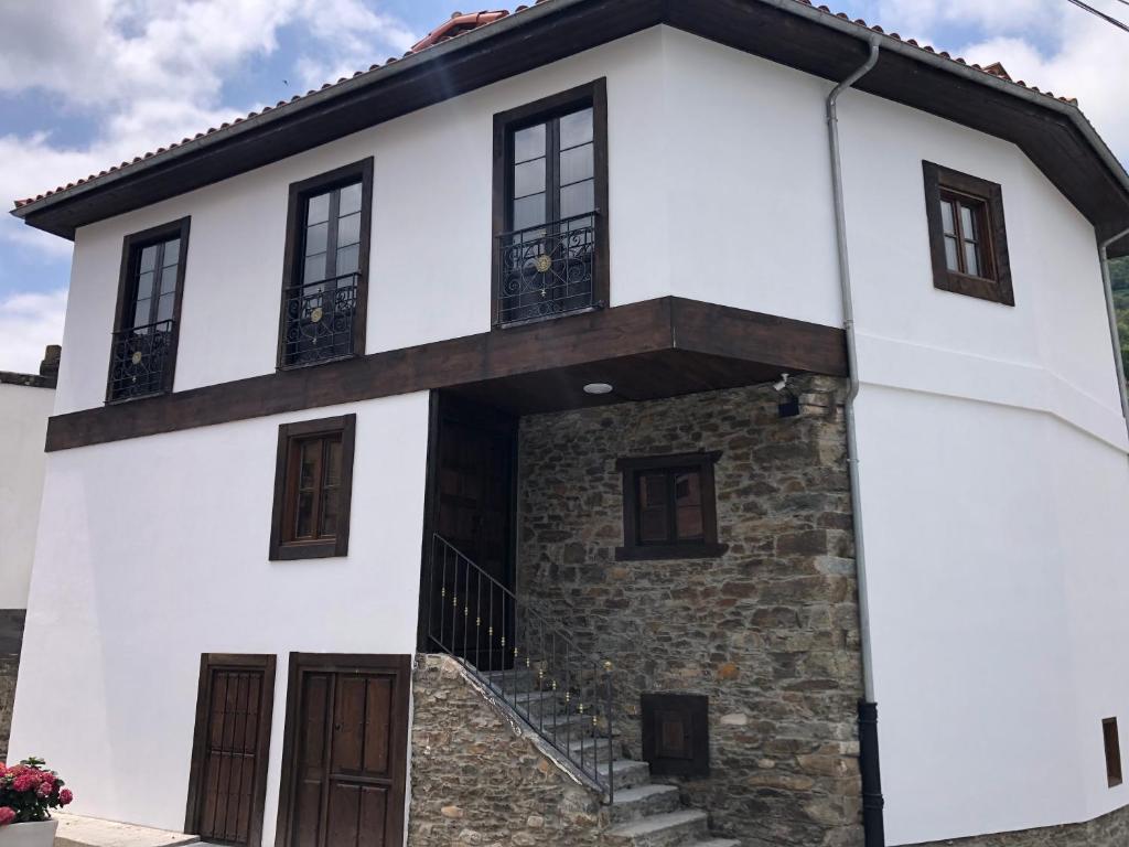 a white house with brown doors and windows at La Capilla del Corral in Cangas del Narcea