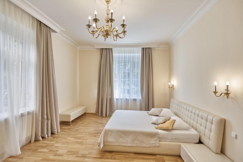 - une chambre avec un grand lit et un lustre dans l'établissement Villa Deluxe Apartments, à Karlovy Vary