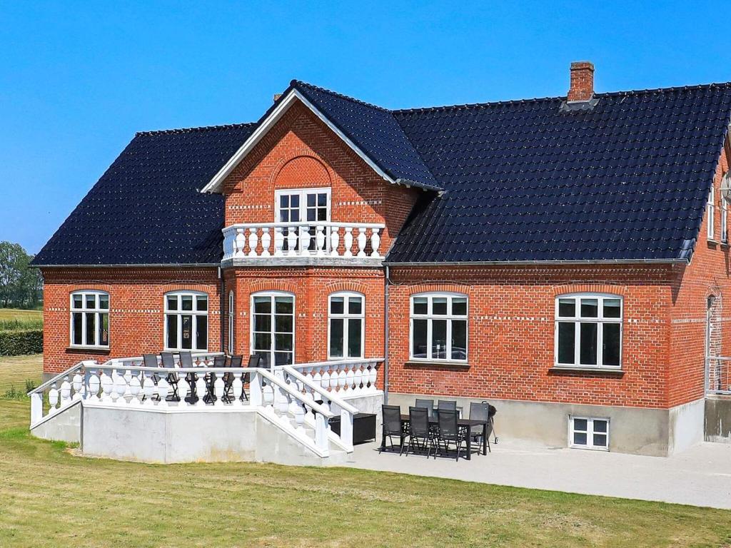 ein großes rotes Backsteinhaus mit einer großen Terrasse in der Unterkunft 12 person holiday home in Nyborg in Nyborg