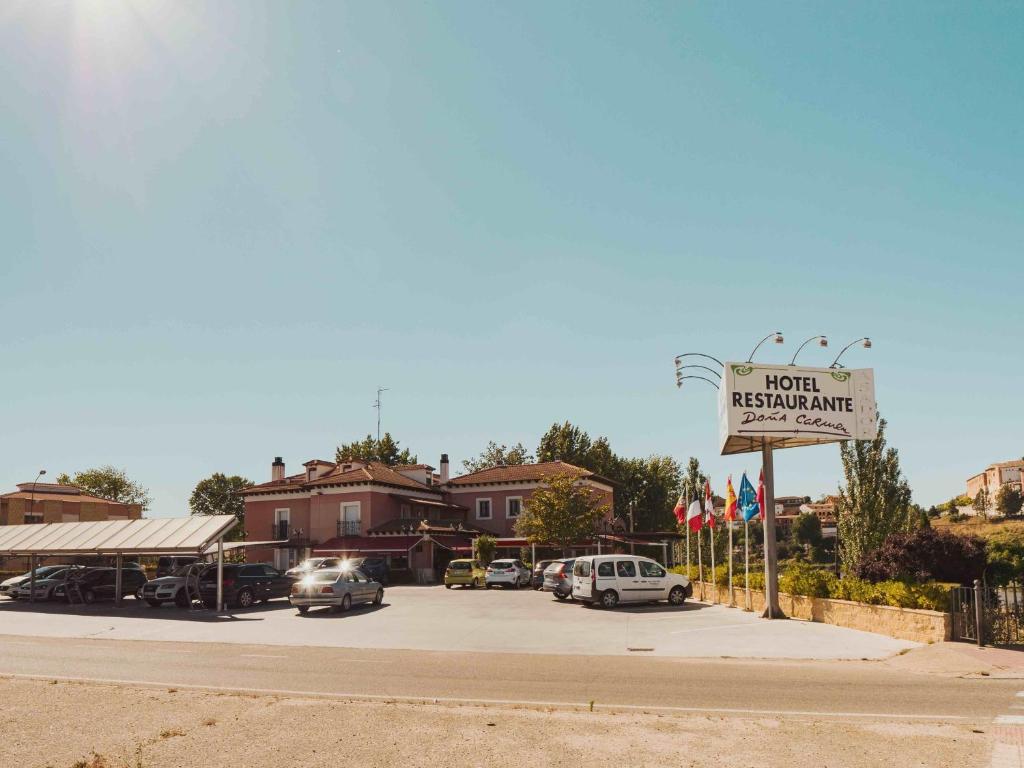 a sign for a hotel with cars parked in a parking lot at Hotel Doña Carmen in Tordesillas