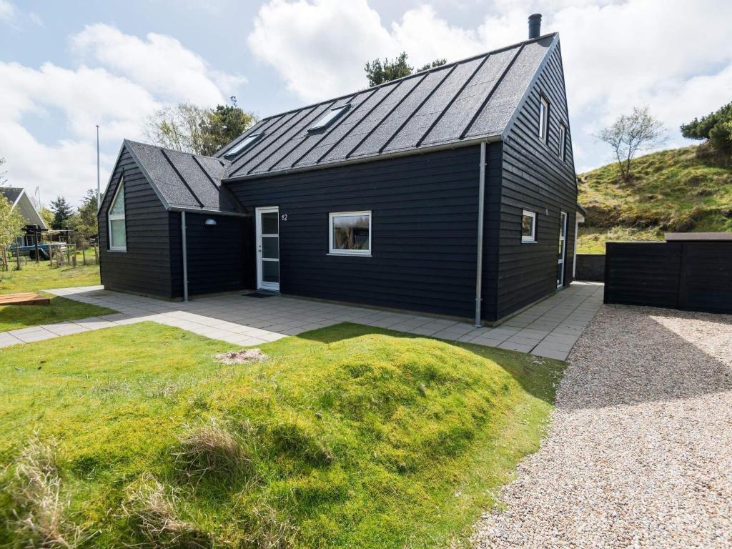 uma casa negra com um telhado inclinado em Holiday home Fanø L em Fanø