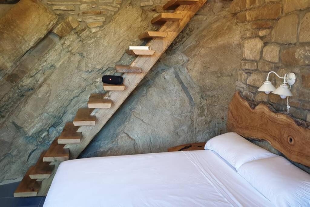 1 dormitorio con cama y pared de piedra en Casa nella Roccia, en Castelmezzano