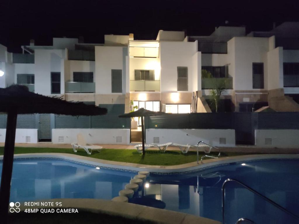 a swimming pool in front of a building at night at CHALET ADOSADO DULCINEA Alcossebre in Alcossebre