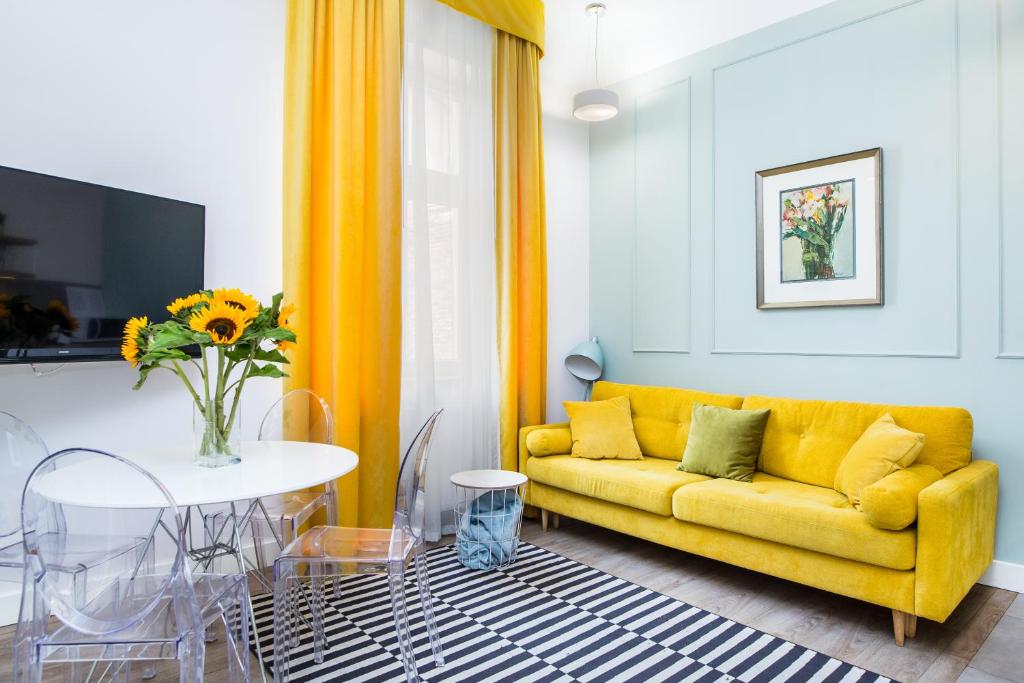 a living room with a yellow couch and a table at Cracow Rentals Zacisze in Kraków