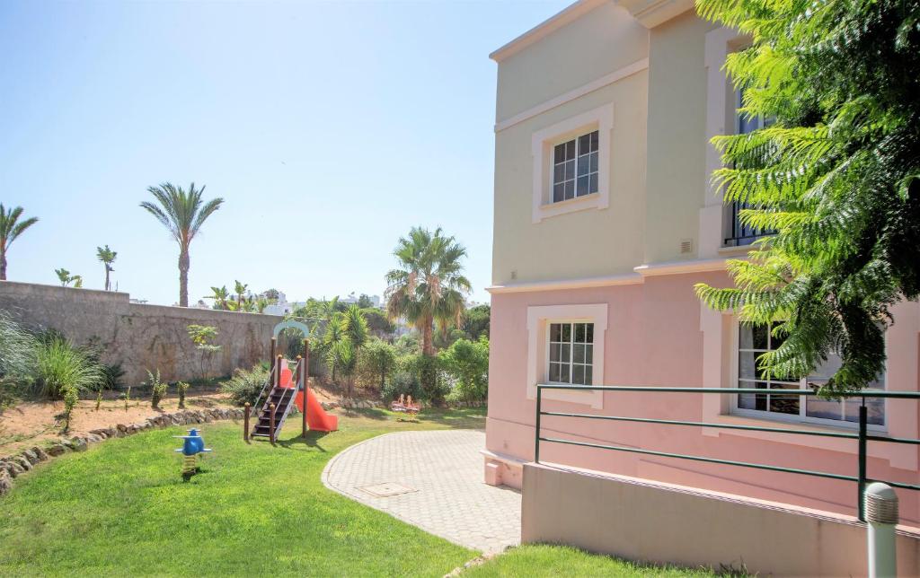 a child playing in a yard next to a house at Aquamar Albufeira Aparthotel in Albufeira