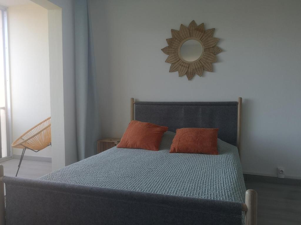 a bed with two orange pillows and a mirror at ESCALE AU GRAU DU ROI in Le Grau-du-Roi