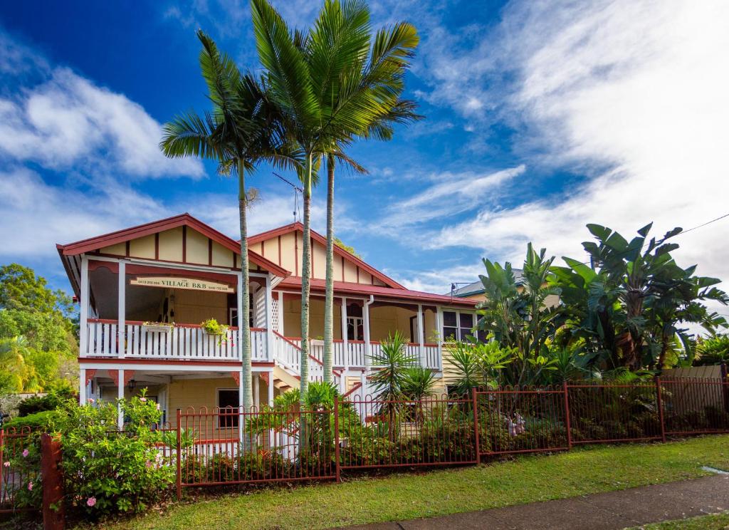 a house with palm trees in front of a fence at The Village B&B in Gold Coast