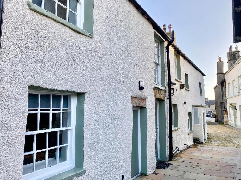 a white house with green windows on a street at The Cottage in Grange Over Sands