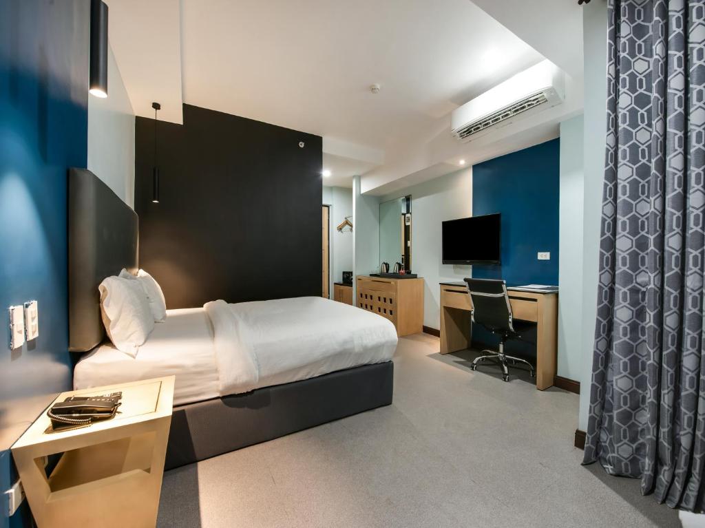 マニラにあるBay Area Suites Manilaのベッド、デスク、テレビが備わるホテルルームです。